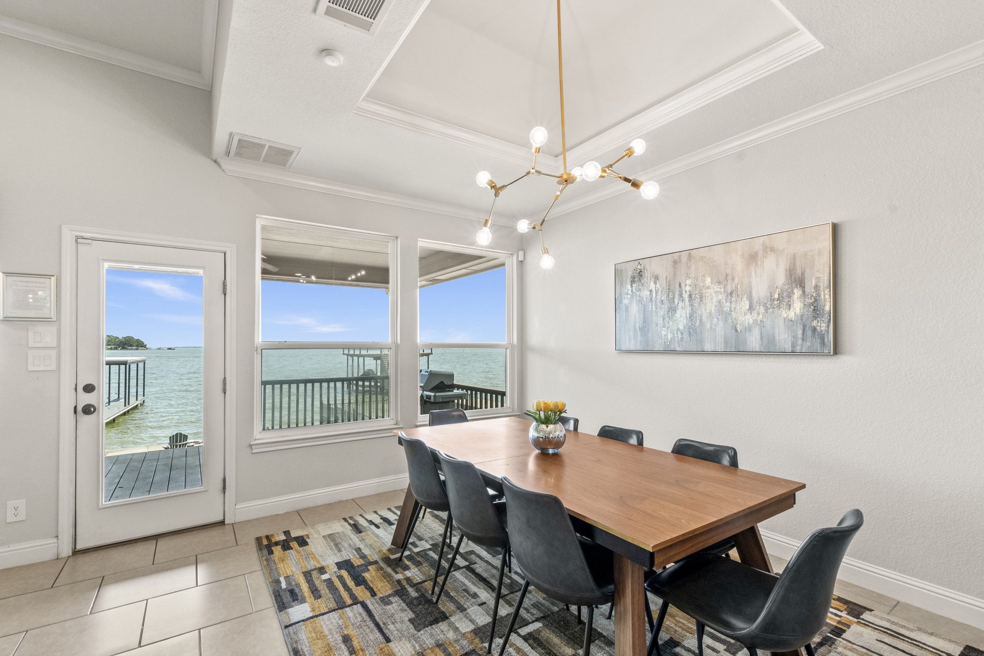 Bright and airy dining area flooded with natural light from large windows, perfectly framing serene water views.